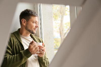 A man with a cup of tea looking out of a window